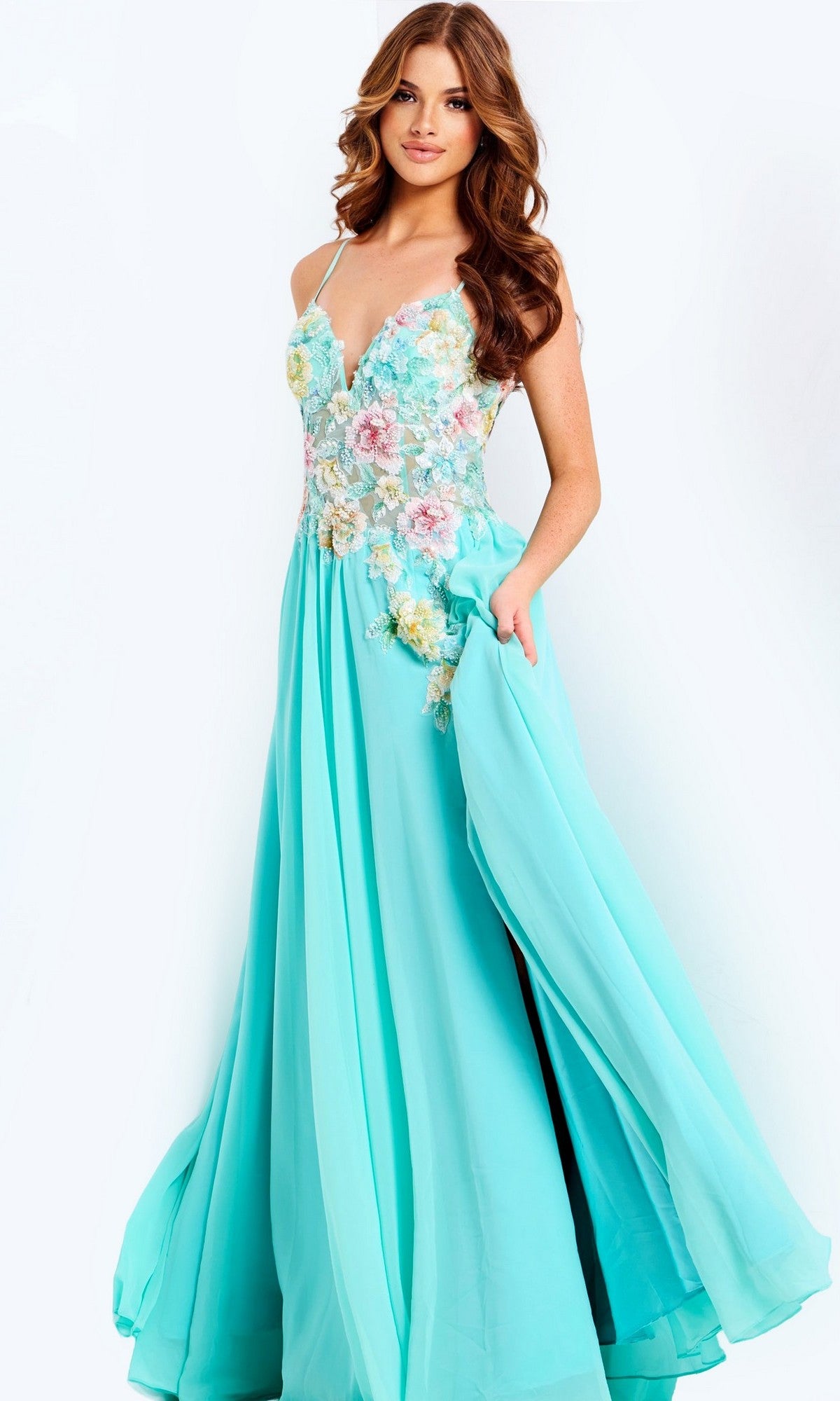 A woman stands against a light background, wearing the Jovani 49633 long prom dress in aqua, featuring floral appliques and a sheer corset bodice.